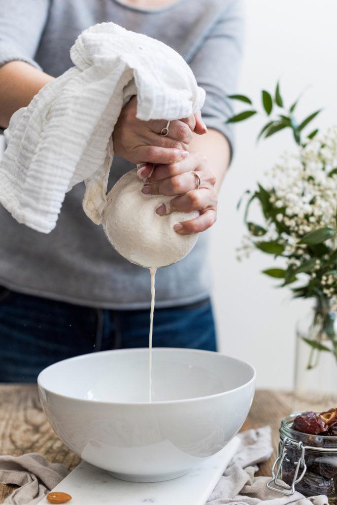 Die selbst gemachte Mandelmilch von Verena von Sweets & Lifestyle®wird durch ein Baumwolltuch gedrückt