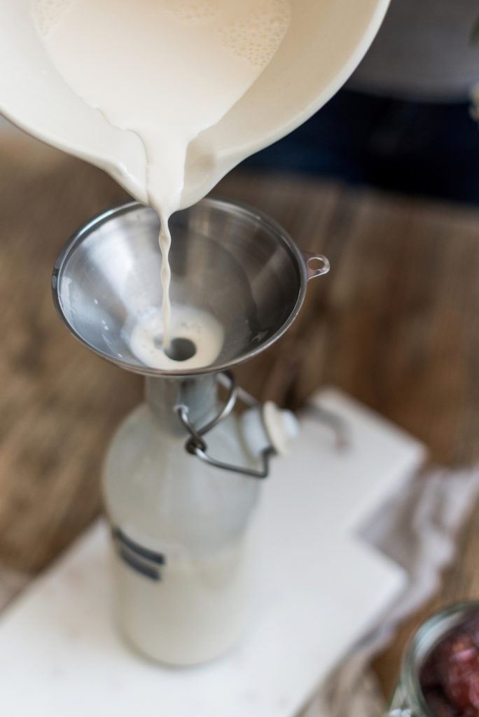 Selbst gemachte Mandelmilch von Verena von Sweets & Lifestyle® wird mit einem Trichter in eine Flasche gefüllt