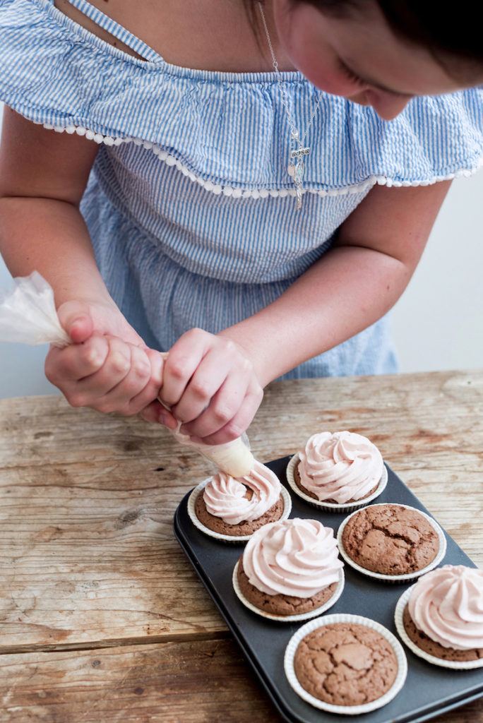 Kind beim Verzieren der Erdbeercupcakes nach einem Rezept von Sweets & Lifestyle®