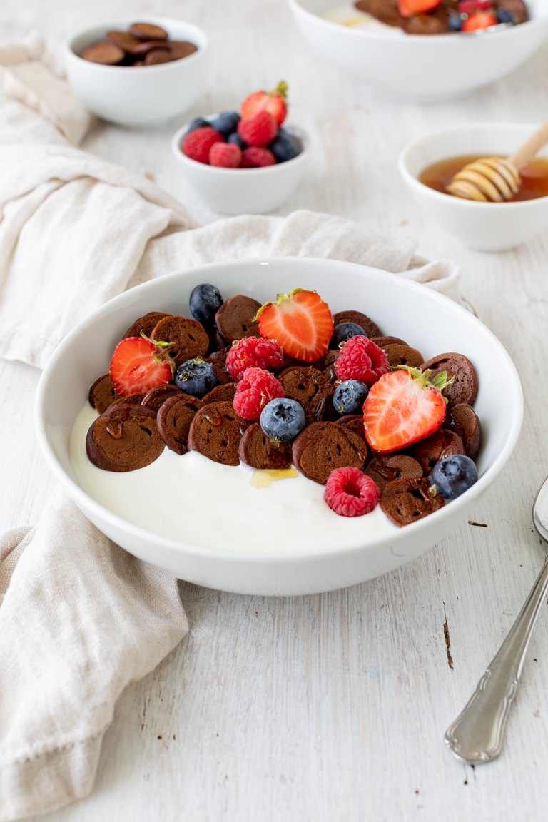 Mini Pancakes mit Kakao serviert mit Joghurt und frischen Beeren als leckeres Fruehstueck nach einem Rezept von Sweets & Lifestyle®