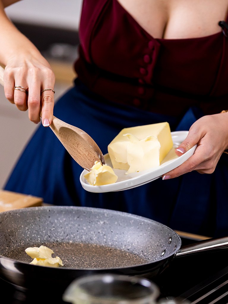 Foodbloggerin Verena Pelikan gibt fuer die Zubereitung einer Pfeffersauce als ersten Butter in eine Pfanne