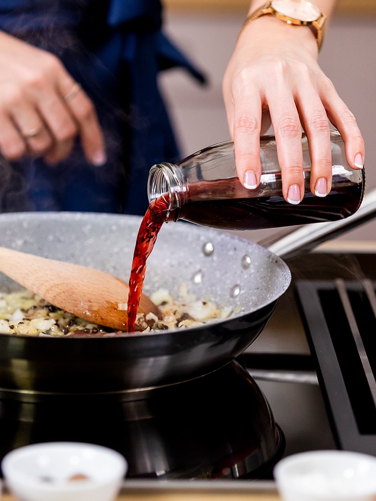 Foodbloggerin Verena Pelikan loescht glasig geduenstete Zwiebel mit Pfeffer mit Portwein ab