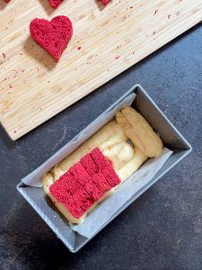 Ausgestochene Herzen werden in die Kastenform geschichtet fuer die Herstellung vom Herzkuchen von Foodbloggerin Verena Pelikan