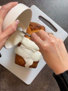 Fertiger Herzkuchen wird mit Zuckerglasur uebergossen und anschliessend mit Zuckerstreusel verziert