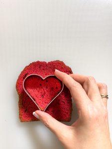 Herz wird aus roten Ruehrkuchen fuer die Herstellung vom Herzkuchen nach einem Rezept von Foodbloggerin Verena Pelikan ausgestochen