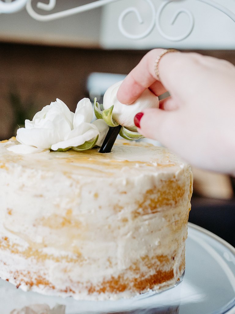 Mit Frischhaltefolie umwickelter Blumenstiel wird von Foodbloggerin Verena Pelikan in Strohhalm gegeben und in die Hochzeitstorte gesteckt