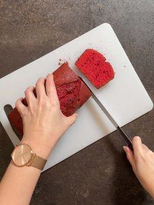 Roter Ruehrkuchen wird in Scheiben geschnitten fuer die Herstellung der Herzen fuer den Herzkuchen nach einem Rezept von Foodbloggerin Verena Pelikan
