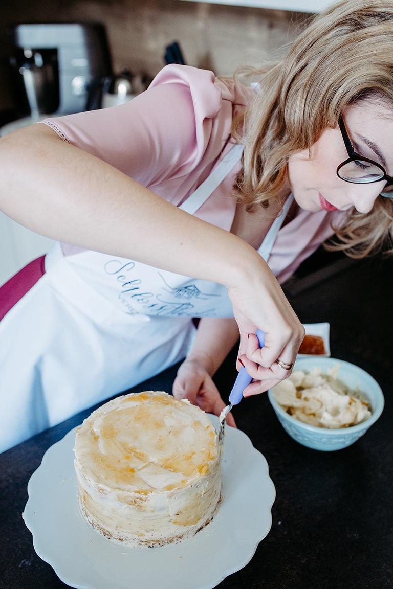 Weisse Sachertorte wird mit Swiss Meringue Buttercream und Marmelade von Foodbloggerin Verena Pelikan verziert um eine selbst gemachte Hochzeitstorte zu werden