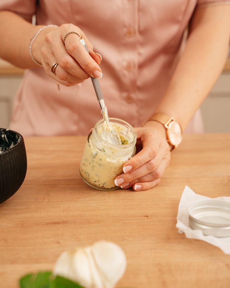 Foodbloggerin Verena Pelikan fuellt die wuerzige selbst gemachte Kraeuterbutter in ein Glas