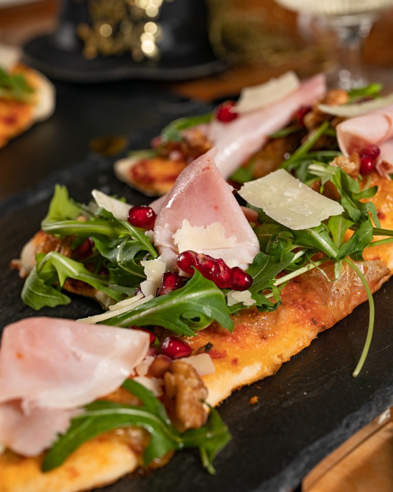 Herzhafte Pizza belegt mit Rucola Schinken Granatapfelkernen und Walnuessen nach einem leckeren Rezept von Foodbloggerin Verena Pelikan