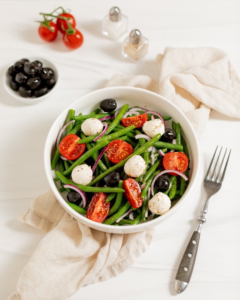 Leckerer Fisolensalat mit Tomaten Mozzarella Oliven und roter Zwiebel als Beilage zu Gegrilltem gemacht nach einem Rezept von Foodbloggerin Verena Pelikan