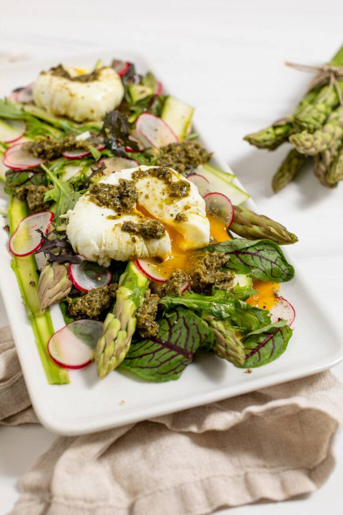 Blattsalat mit gruenem Spargel Radieschen Pesto und pocheiertem Ei als Fruehlingssalat serviert nach einem Rezept von Foodbloggerin Verena Pelikan