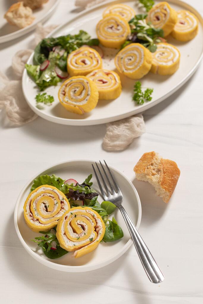 Palatschinken Roellchen mit Schinken und Kaese serviert mit Blattsalat als leckere Vorspeise