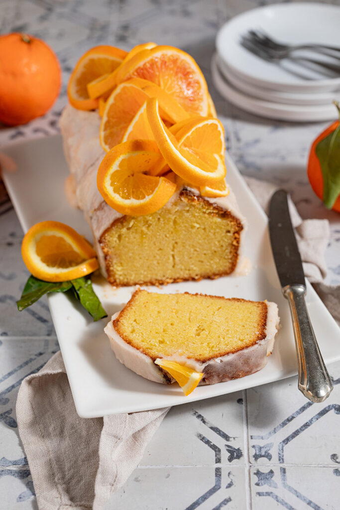 angeschnittener saftiger Orangenkuchen mit Zuckerglasur auf Kuchenplatte